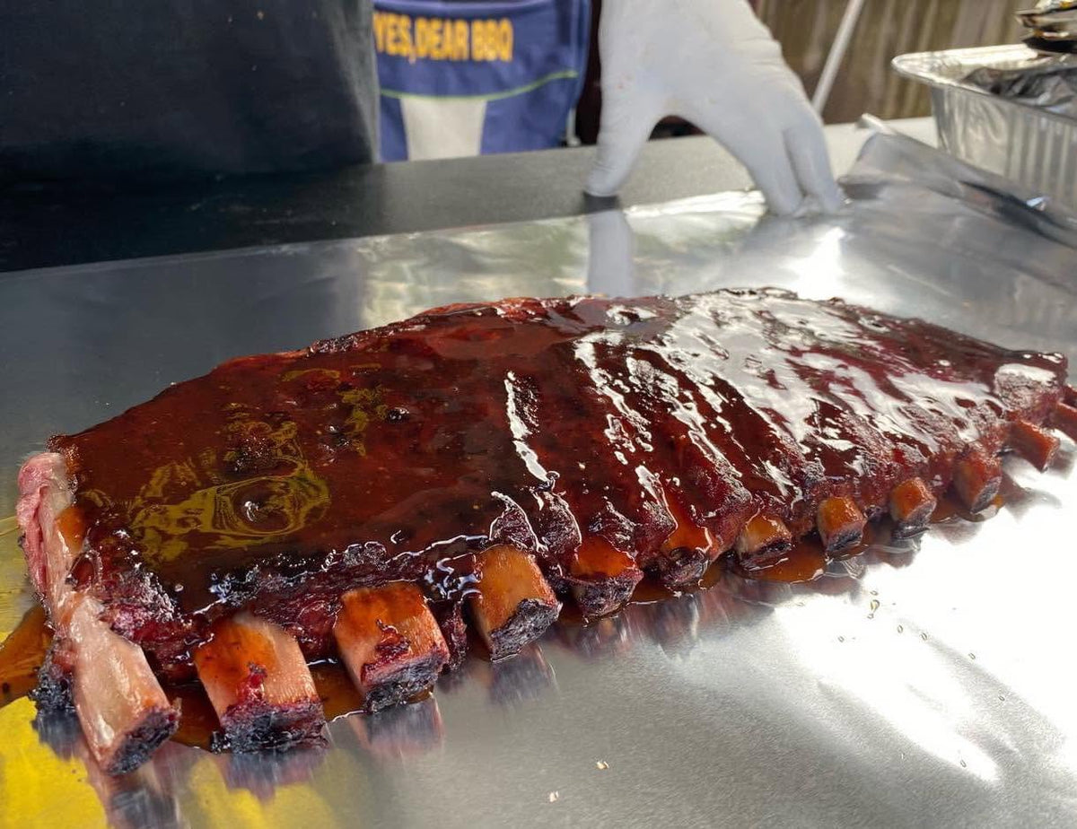 pork ribs resting on a sheet of aluminum foil on a grill table
